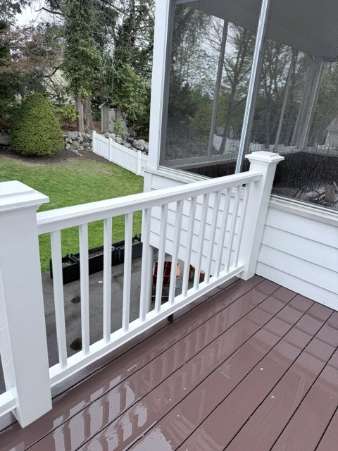 Pressure washing technician cleaning a weathered wood deck in Belmont, MA